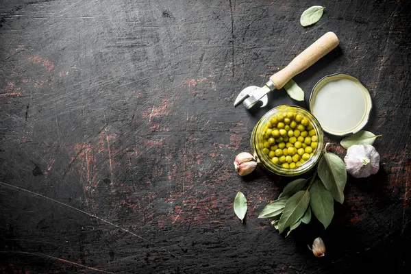 Defne yaprağı ve sarımsak karanfil ile konserve yeşil bezelye. Koyu rustik arka plan üzerinde