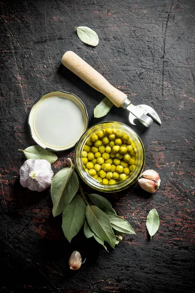 Defne yaprağı ve sarımsak karanfil ile konserve yeşil bezelye. Koyu rustik arka plan üzerinde