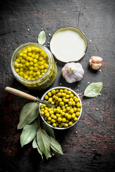 Konserve yeşil bezelye ile açık cam kavanoz. Koyu rustik arka plan üzerinde