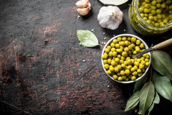 Konserve yeşil bezelye ile açık cam kavanoz. Koyu rustik arka plan üzerinde