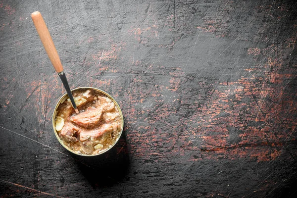 stock image Canned meat in a tin with a spoon. On dark rustic background