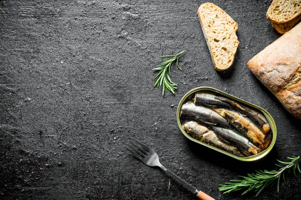 Ekmek ve biberiye dilimleri ile sprats. Siyah rustik arka plan üzerinde