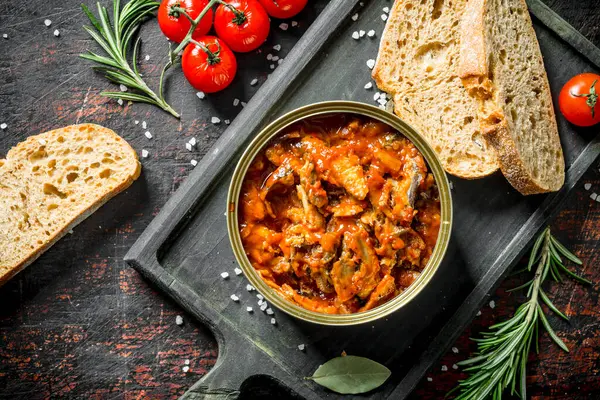 Ekmek, kiraz domates ve biberiye ile domates soslu sprat. Koyu rustik arka plan üzerinde