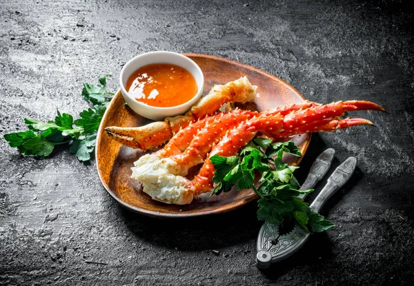 Maydanoz ve soslu bir tabakta taze yengeç. Siyah rustik arka plan üzerinde