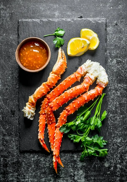 Sos, maydanoz ve limon dilimleri ile bir taş tahta üzerinde Yengeç. Koyu rustik arka plan üzerinde