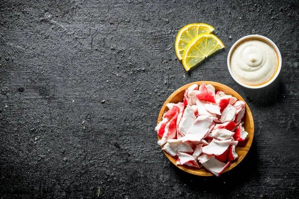 Sos lu ve limon dilimleri olan bir tabakta yengeç eti. Siyah rustik arka plan üzerinde