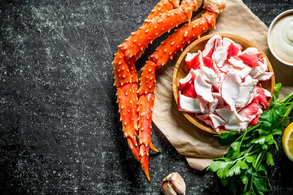 Maydanoz ve sos ile kağıt üzerinde bir tabakta yengeç eti. Koyu rustik arka plan üzerinde