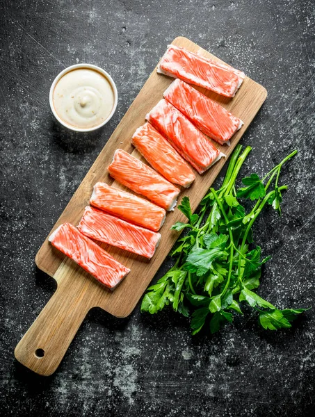 Yengeç yeşillik ve sos ile ahşap kesme Tahtası üzerinde sopalarla. Koyu rustik arka plan üzerinde