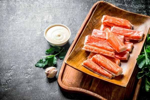 Yengeç sarımsak karanfil, sos ve maydanoz ile plaka sopalarla. Koyu rustik arka plan üzerinde