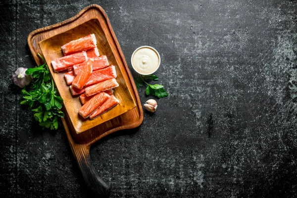 Yengeç yeşillik, sos ve sarımsak ile kesme Tahtası üzerinde sopalarla. Koyu rustik arka plan üzerinde