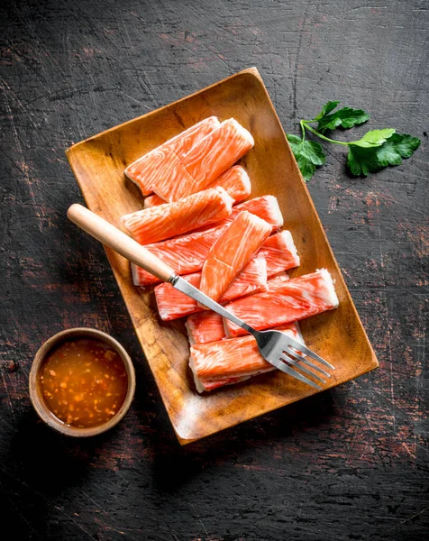 Yengeç çatal ve soslu bir tabağa yapışır. Koyu rustik arka plan üzerinde