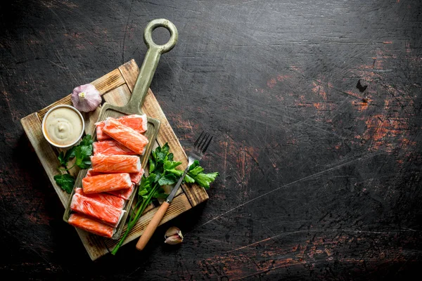 Yengeç otlar, sarımsak ve sos ile ahşap tepsiye sopalarla. Koyu rustik arka plan üzerinde