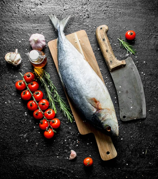 Bir bıçak, domates ve sarımsak ile kesme Tahtası üzerinde çiğ balık. Siyah rustik arka plan üzerinde