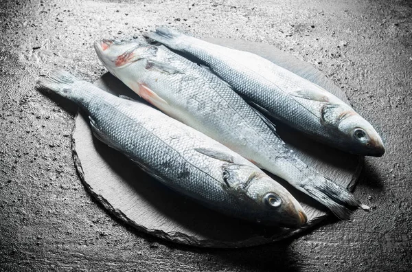 stock image Fresh raw fish on a stone Board. On black rustic background