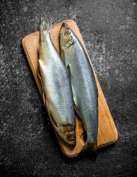 stock image Salted herring on a cutting Board. On dark rustic background