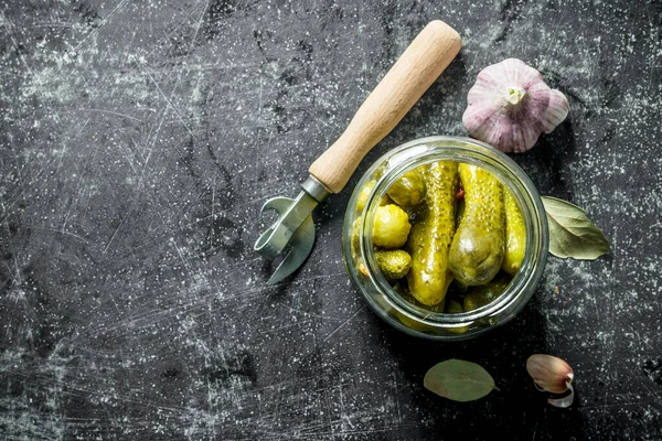 stock image Open jar with preserved cucumbers with garlic. On dark rustic background