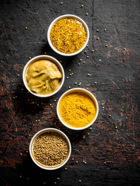 stock image Different kinds of mustard in the bowls. On dark rustic background