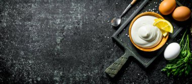 Yumurta, maydanoz, sarımsak ve limon dilimleri ile bir kesme Tahtası üzerinde Mayonez. Koyu rustik arka plan üzerinde