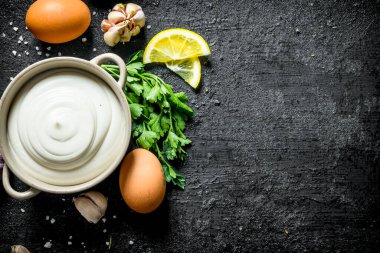 Otlar, yumurta, sarımsak ve limon ile mayonez. Siyah rustik arka plan üzerinde
