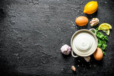 Yumurta, sarımsak ve limon ile mayonez. Siyah rustik arka plan üzerinde