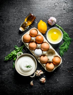 Yumurta, yağ, otlar ve sarımsak karanfil ile mayonez. Siyah rustik arka plan üzerinde