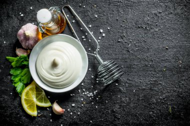 Maydanoz, zeytinyağı ve limon dilimleri ile mayonez. Siyah rustik arka plan üzerinde