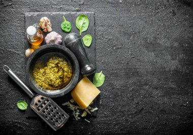 Fesleğen, yağ ve Parmesan ile bir taş Tahta üzerinde Pesto sosu. Siyah rustik arka plan üzerinde