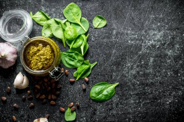 Çam fıstığı, sarımsak ve fesleğen ile bir kavanozda Pesto sosu. Koyu rustik arka plan üzerinde