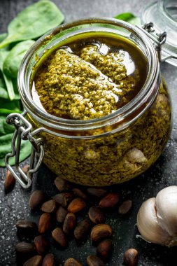 Çam fıstığı, sarımsak ve fesleğen ile bir kavanozda Pesto sosu. Koyu rustik arka plan üzerinde