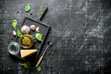 Parmesan, Fesleğen ve sarımsak ile bir kesme Tahtası üzerinde Pesto sosu. Koyu rustik arka plan üzerinde