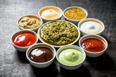 Soslar Seti - ketçap, barbekü sosu, pesto, mayonez, hardal. Koyu rustik arka plan üzerinde