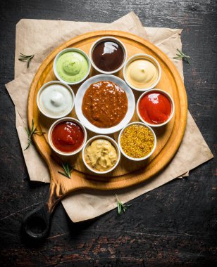 Kağıtlı kesme tahtasında büyük soslar. Koyu rustik arka plan üzerinde