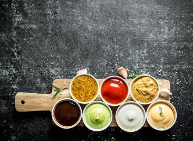 Sarımsak ve biberiye ile ahşap kesme Tahtası üzerinde Soslar. Koyu rustik arka plan üzerinde