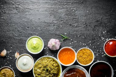 Lezzetli soslu kaseler. Siyah rustik arka plan üzerinde