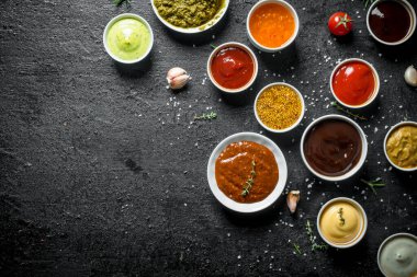 Lezzetli soslu kaseler. Siyah rustik arka plan üzerinde