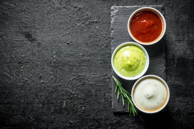 Guacomole sosu, domates sosu ve biberiye ile bir taş Tahta üzerinde mayonez. Siyah rustik arka plan üzerinde