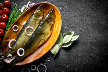 Domates, dereotu ve soğan halkaları ile füme balık. Siyah rustik arka plan üzerinde