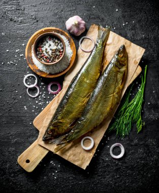 Dereotu, baharat ve soğan ile füme balık. Siyah rustik arka plan üzerinde