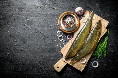 Dereotu, baharat ve soğan ile füme balık. Siyah rustik arka plan üzerinde