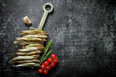 Kiraz domates ve biberiye ile kesme Kurulu füme balık. Koyu rustik arka plan üzerinde