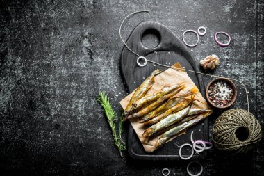 Biberiye, ip, baharat ve sarımsak karanfil ile bir kesme Tahtası üzerinde Füme balık. Koyu rustik arka plan üzerinde