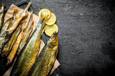 Limon parçaları ile füme balık farklı türde. Siyah rustik arka plan üzerinde