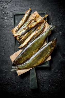 Kesme Tahtası'nda füme balık. Siyah rustik arka plan üzerinde