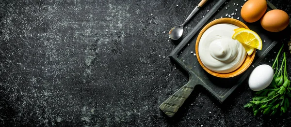 Yumurta, maydanoz, sarımsak ve limon dilimleri ile bir kesme Tahtası üzerinde Mayonez. Koyu rustik arka plan üzerinde