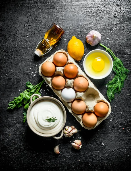 Yumurta, yağ, otlar ve sarımsak karanfil ile mayonez. Siyah rustik arka plan üzerinde