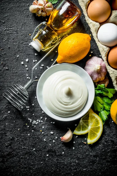 Zeytinyağı, otlar ve yumurta ile mayonez. Siyah rustik arka plan üzerinde