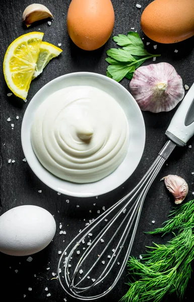 Yumurta, sarımsak ve otlar ile mayonez. Siyah rustik arka plan üzerinde