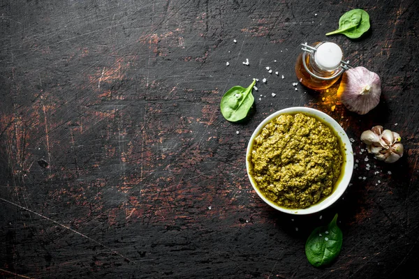 Zeytinyağı, sarımsak ve Fesleğen yaprakları ile kasede Pesto sosu. Koyu rustik arka plan üzerinde