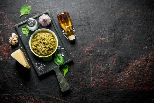 Zeytinyağı, Parmesan, Fesleğen ve sarımsak ile kesme Tahtası üzerinde Pesto sosu. Koyu rustik arka plan üzerinde