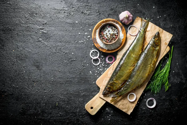 Dereotu, baharat ve soğan ile füme balık. Siyah rustik arka plan üzerinde